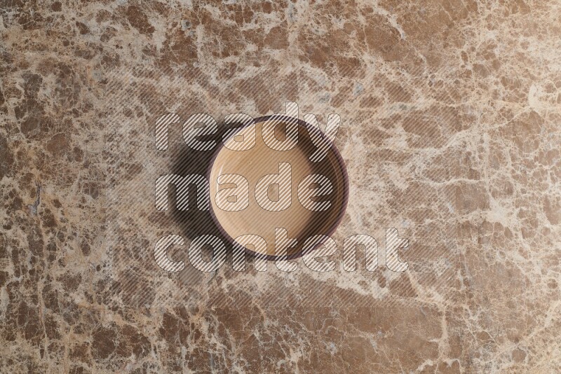 A beige pottery oven plate on beige marble background