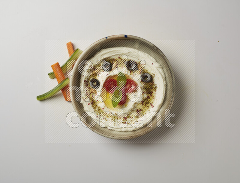 Lebnah garnished with cherry tomato, mint, olives & pine nuts in a grey pottery plate on a white background