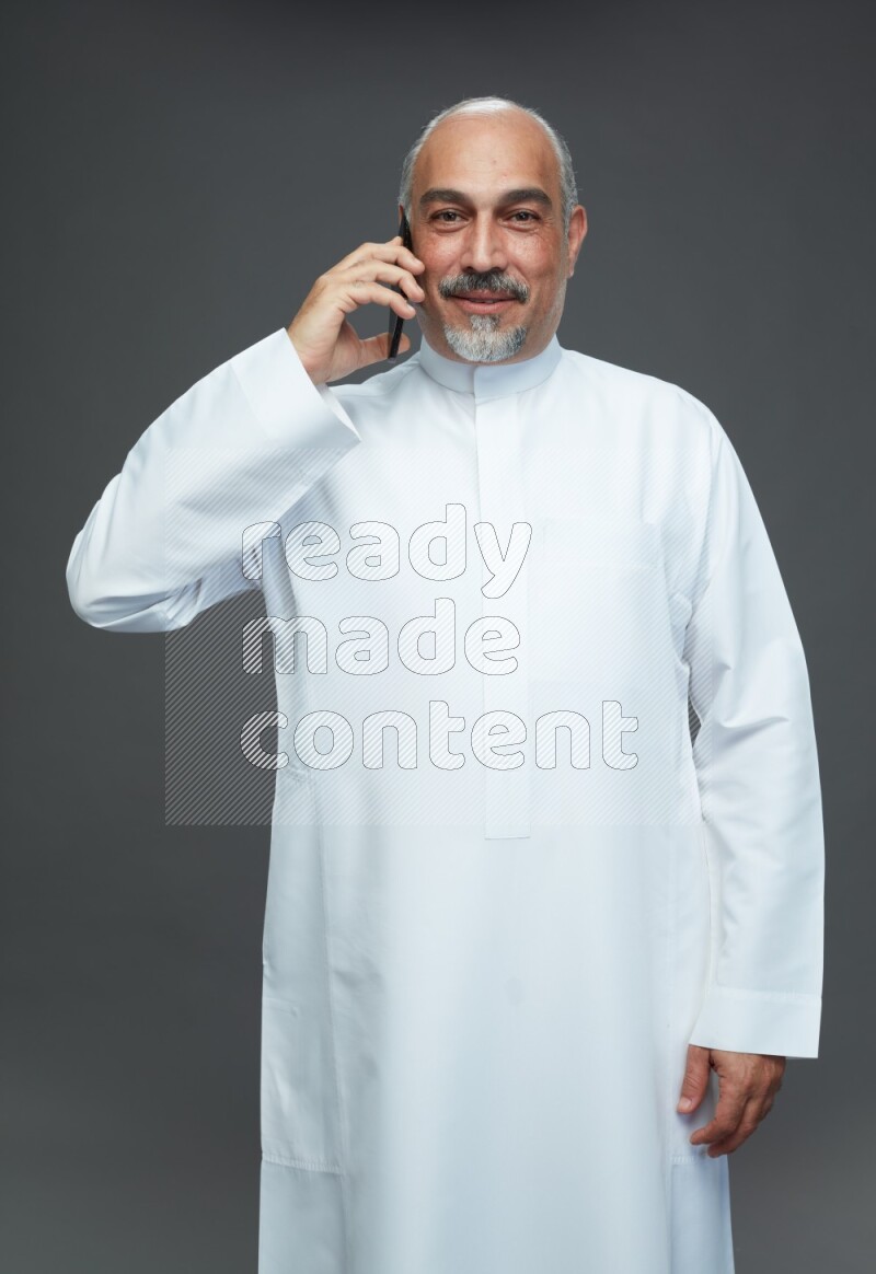 Saudi man without shomag Standing talking on phone on gray background