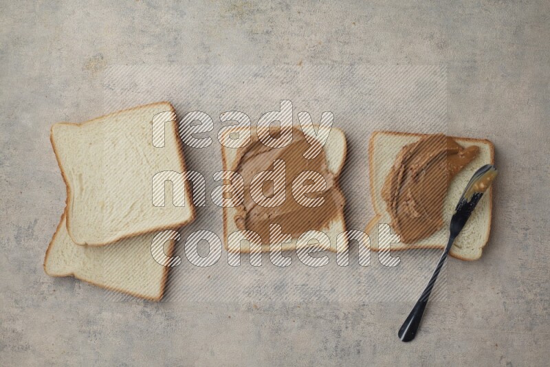Creamy peanut butter on white toast and white toast slices on a light blue textured background