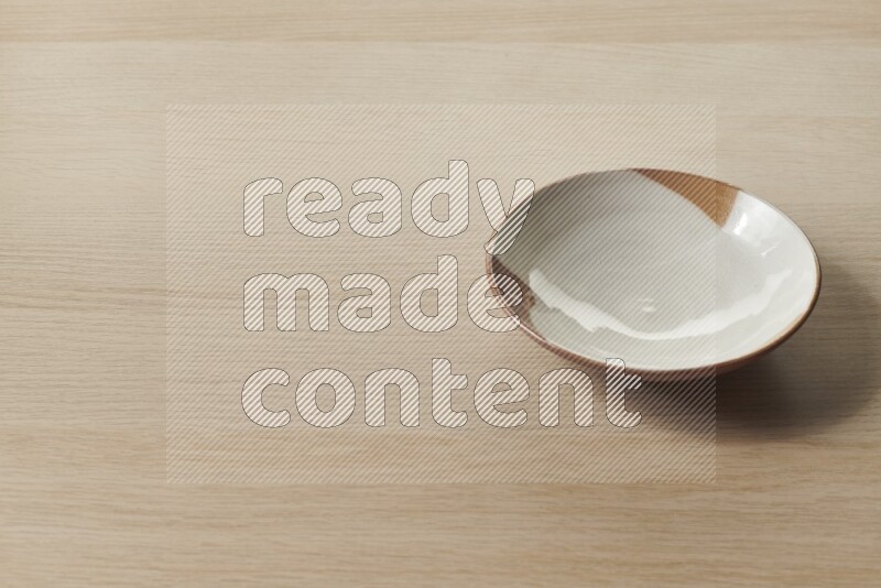 A multicolored pottery plate on light wooden background