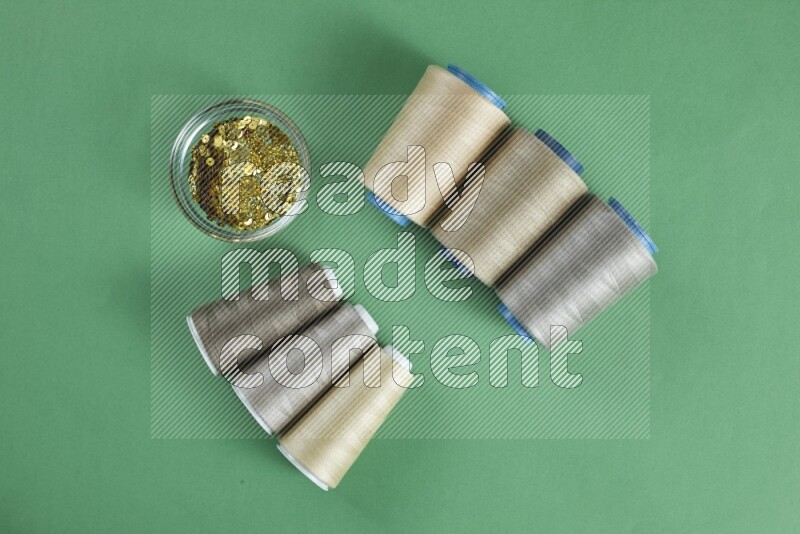 A brown collection of sewing and tailoring tools arranged on a green background