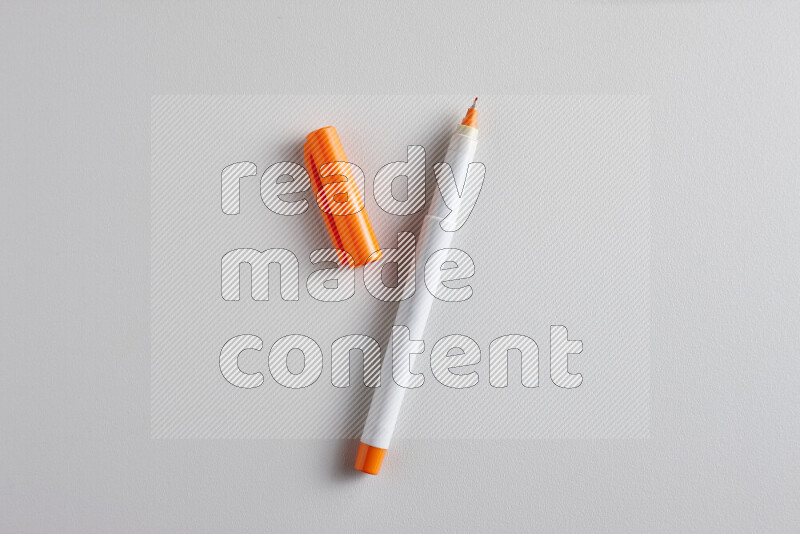 A close-up showing an open single coloring pen with a cap on grey background
