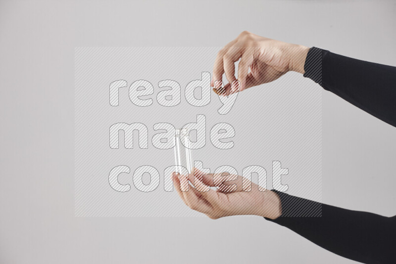 امرأة ترتدي عباءة سوداء تحمل أدوات زجاجية مختلفة في أوضاع متعددة