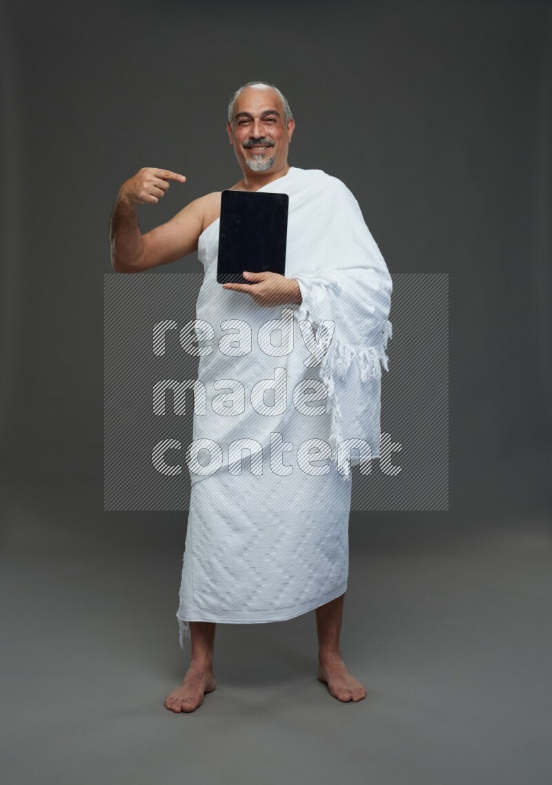 A man wearing Ehram Standing working on tablet on gray background