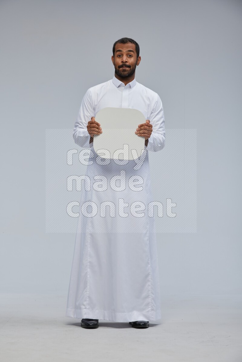 Saudi man wearing Thob standing holding social media sign on Gray background