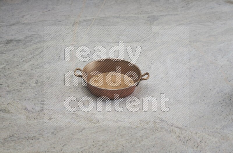 A small copper pan on grey marble background
