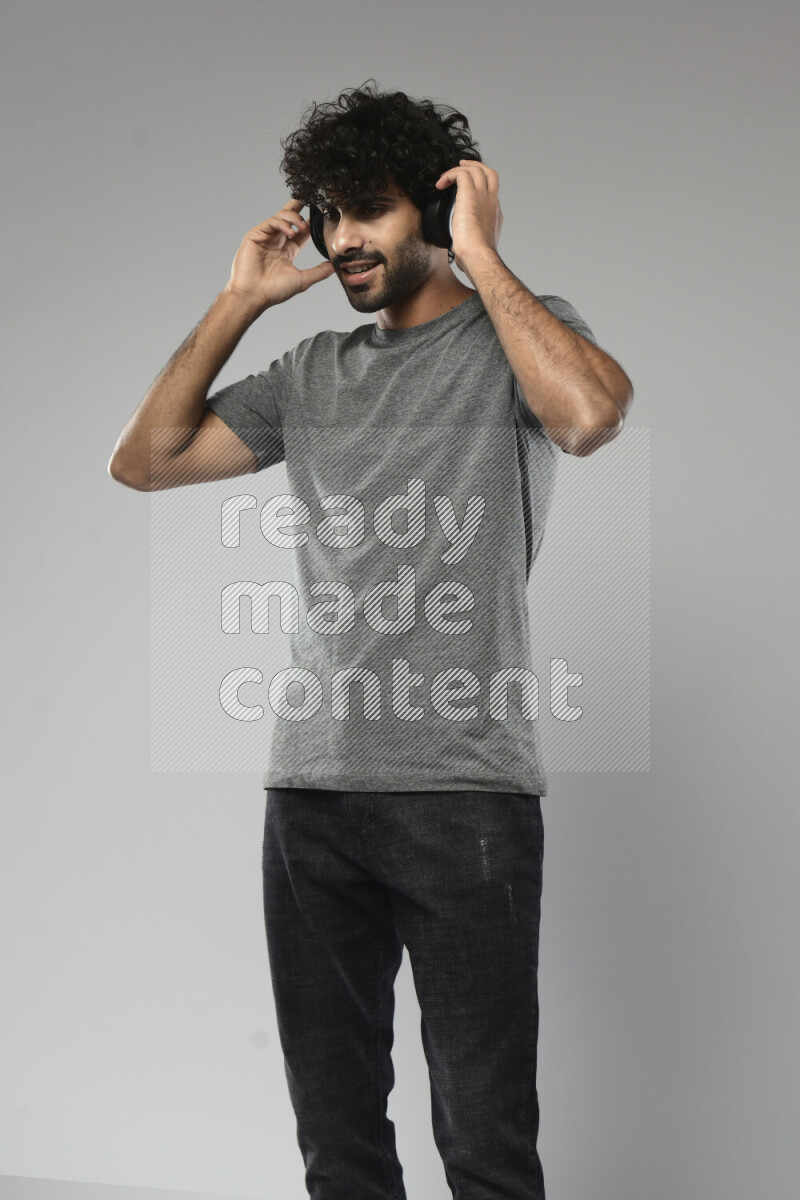 A man wearing casual standing and putting on headphones on white background