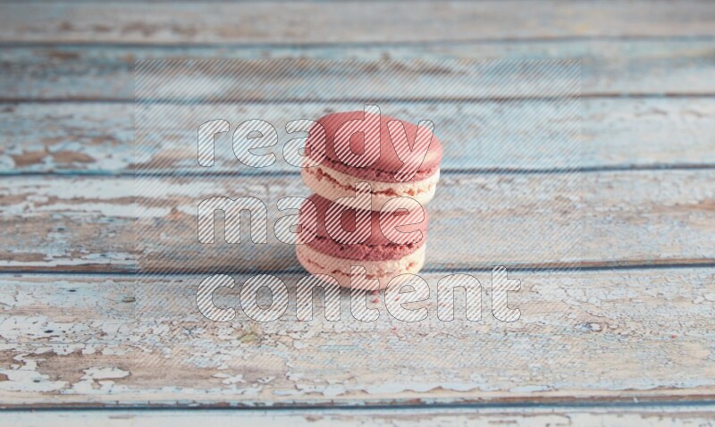 45º Shot of two Pink Litchi Raspberry macarons on light blue wooden background