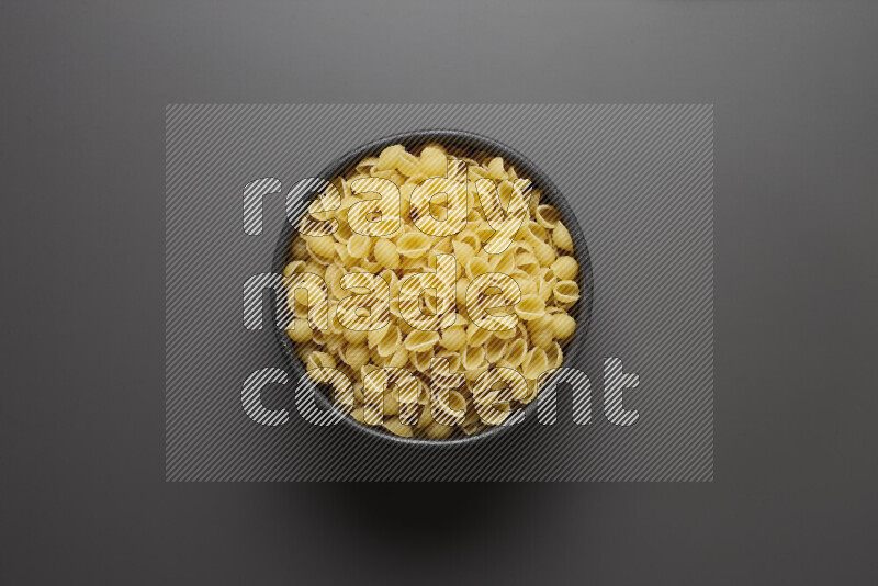 Shells pasta in a pottery bowl on grey background