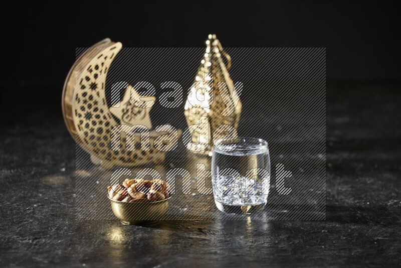 Nuts in a metal bowl with water beside golden lanterns in a dark setup