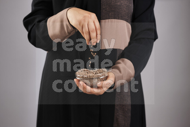 Woman in abaya holding different kinds of legumes in different positions