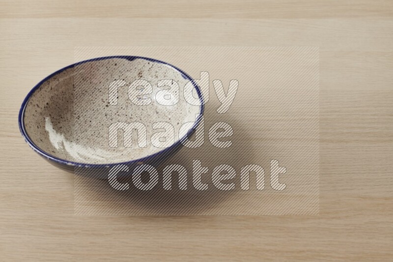 A multicolored pottery bowl on light wooden background