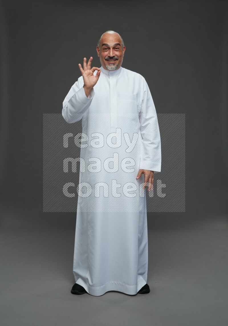 Saudi man without shomag Standing Interacting with the camera on gray background