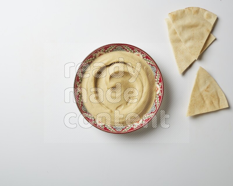 Plain Hummus in a red plate with patterns on a white background