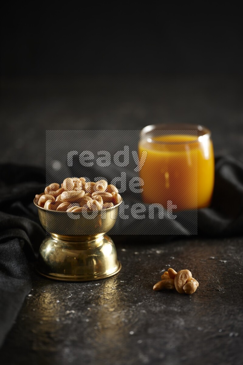 Nuts in a metal bowl with qamar eldin and a napkin in a dark setup