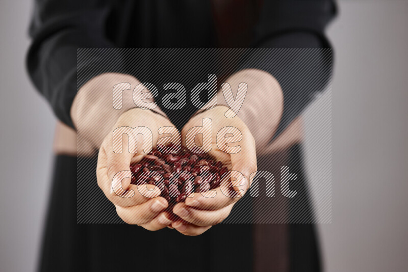 Woman in abaya holding different kinds of legumes in different positions