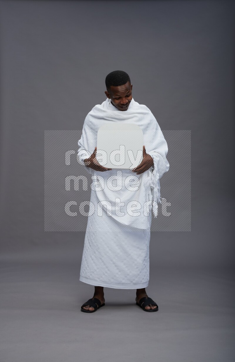 A man wearing Ehram Standing holding social media sign on gray background