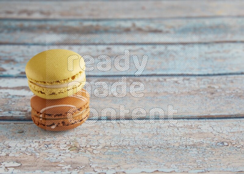 45º Shot of of two assorted Brown Irish Cream, and Yellow Lime macarons on light blue background