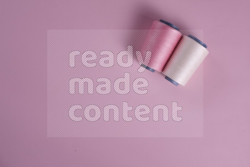 مجموعة من أدوات الخياطة والتفصيل بيضاء وزهرية اللون على خلفية زهرية