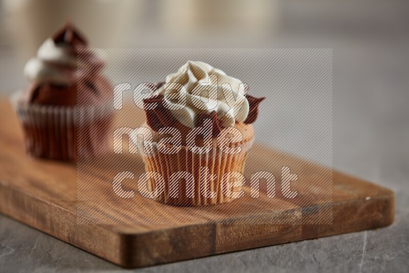 Vanilla cupcake topped with cream on a wooden board