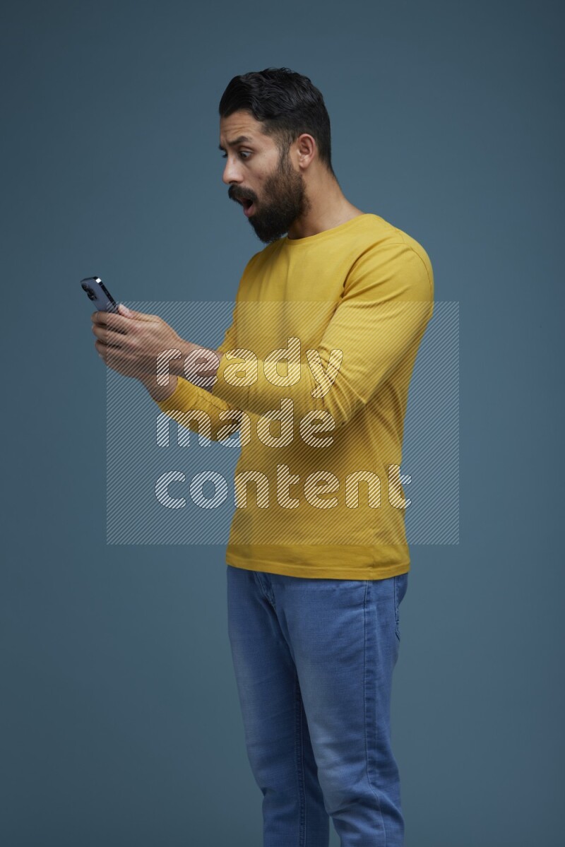 Man typing on his phone in a blue background wearing a yellow shirt
