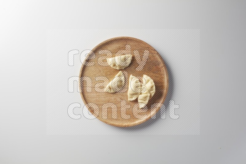Five Sambosas on a wooden round plate on a white background