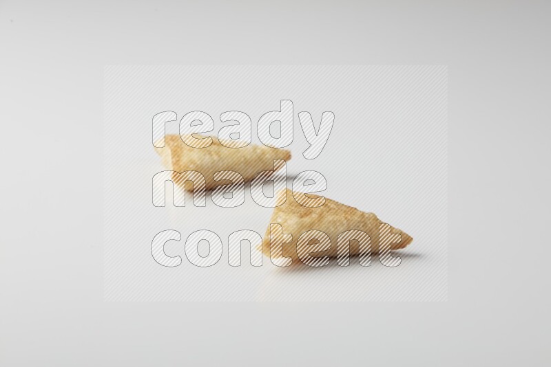 Two fried sambosas on a white background