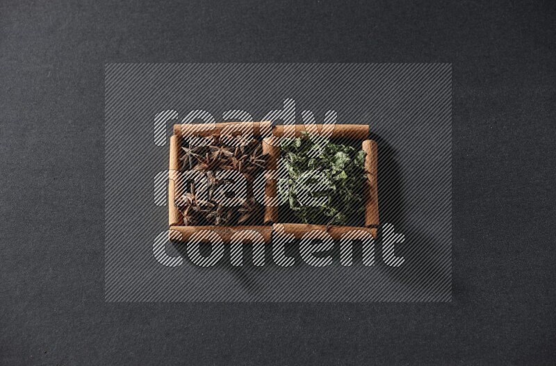 2 squares of cinnamon sticks full of star anise and dried mint leaves on black flooring