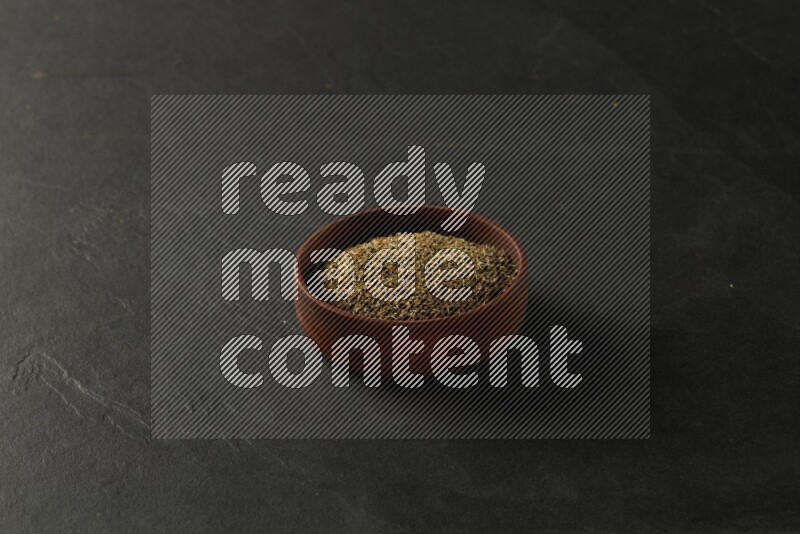 wooden round sauce bowl filled with herbs on grey textured countertop