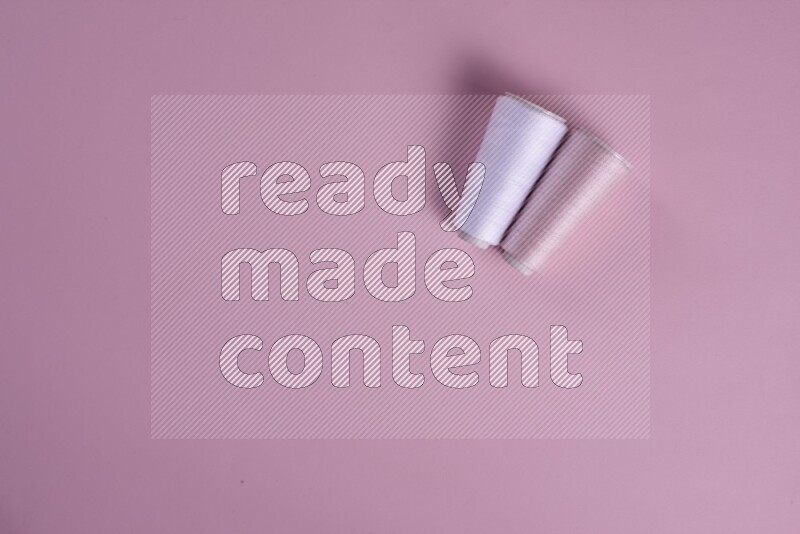 مجموعة من أدوات الخياطة والتفصيل بيضاء وزهرية اللون على خلفية زهرية