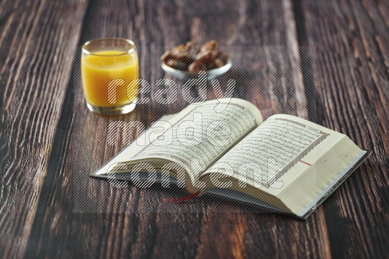Quran with dates, prayer beads and different drinks all placed on wooden background