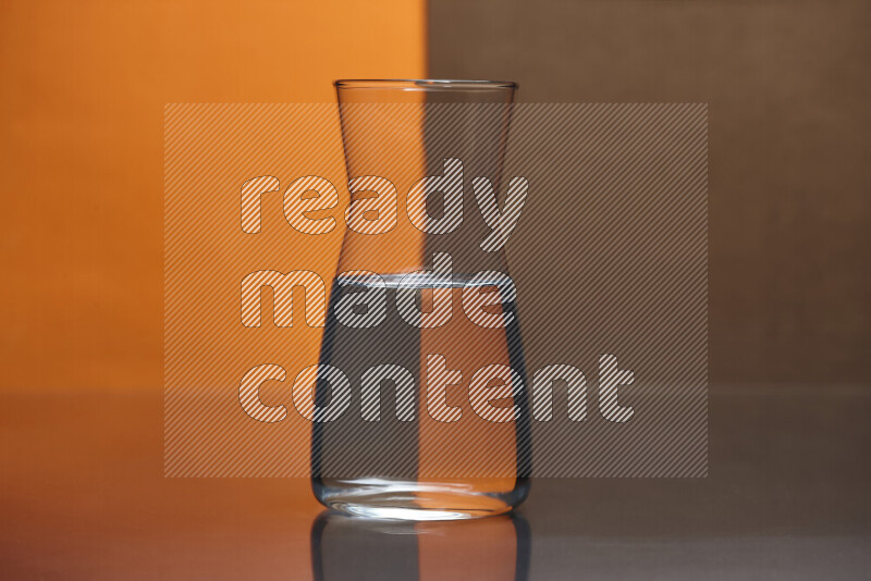 The image features a clear glassware filled with water, set against orange and brown background