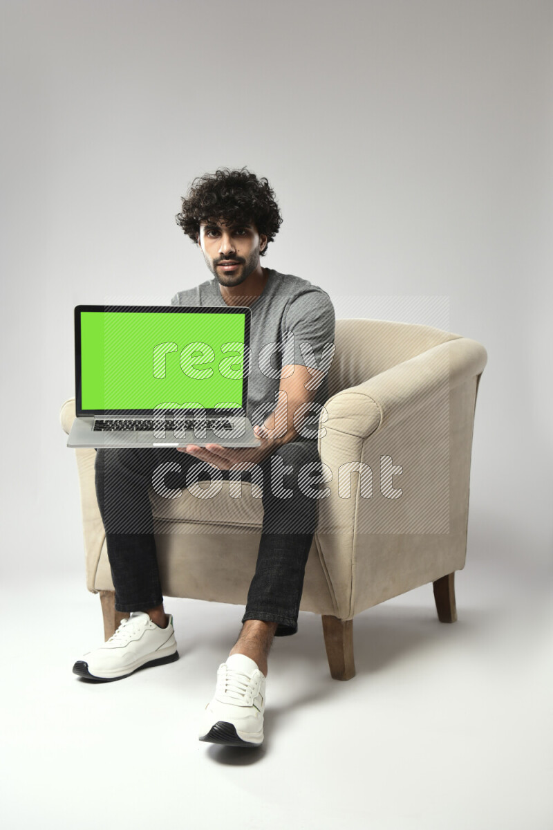 A man wearing casual sitting on a chair showing a laptop screen on white background