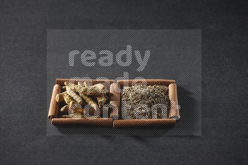 2 squares of cinnamon sticks full of cumin and turmeric fingers on black flooring