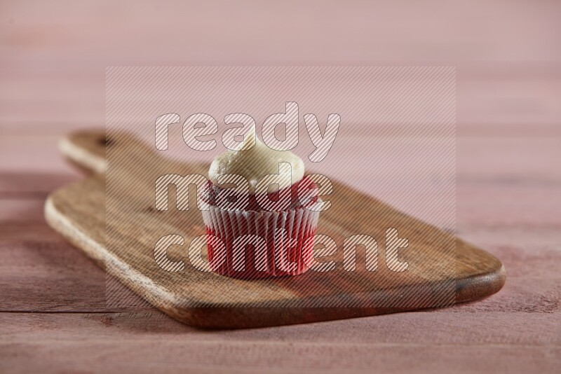 Red velvet mini cupcake topped with cream on a wooden board
