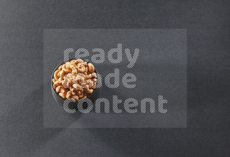 وعاء فخاري أسود ممتلئ بالكاجو على خلفية سوداء