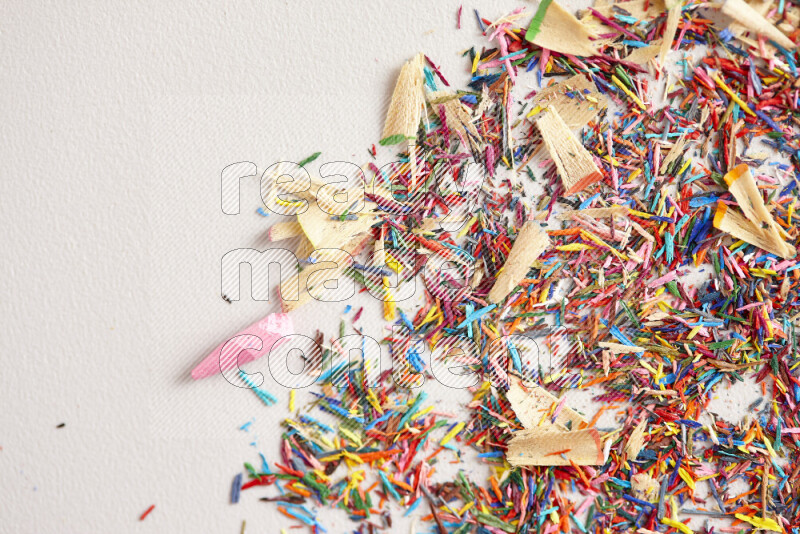 This image showcases a vibrant multicolored pencil shavings scattered on grey background