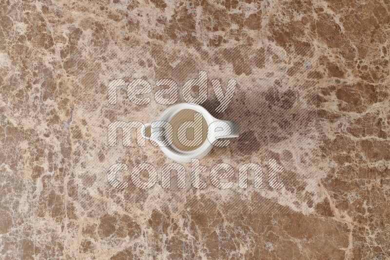 A ceramic milk jug on beige marble background