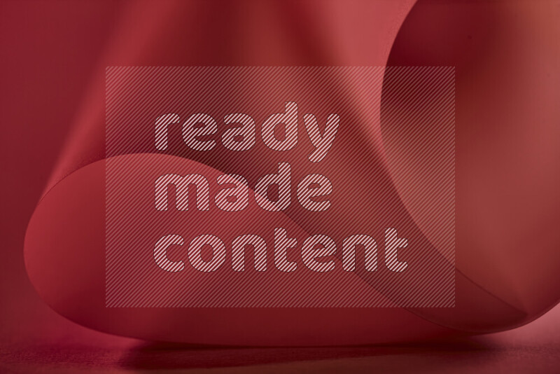 An abstract art piece displaying smooth curves in red gradients created by colored light