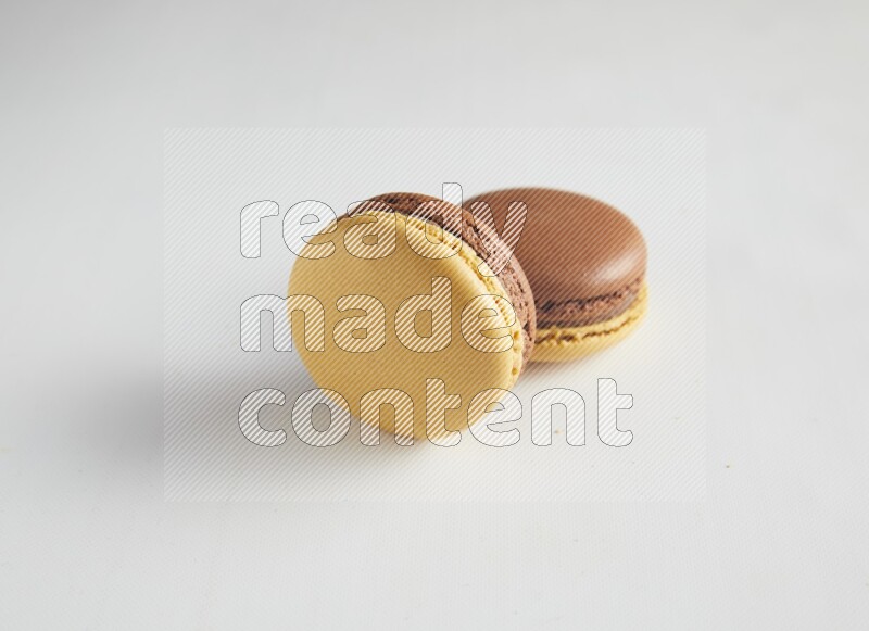 45º Shot of two Yellow and Brown Chai Latte macarons on white background