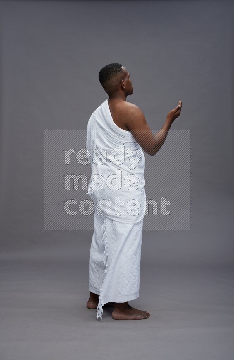 A man wearing Ehram Standing dua'a on gray background