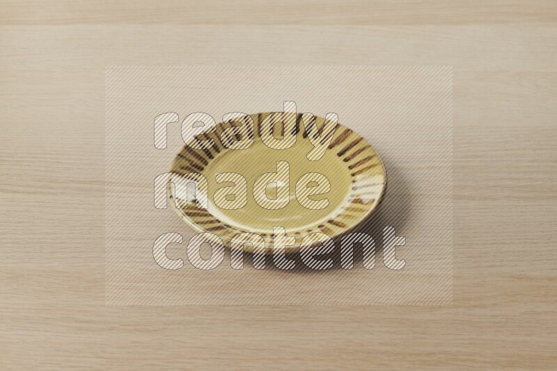 A multicolored pottery plate on light wooden background