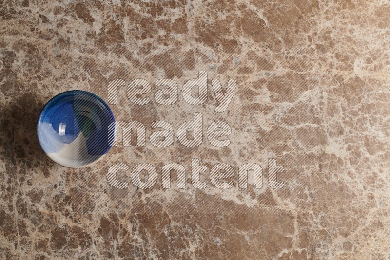 A multicolored pottery bowl on beige marble background
