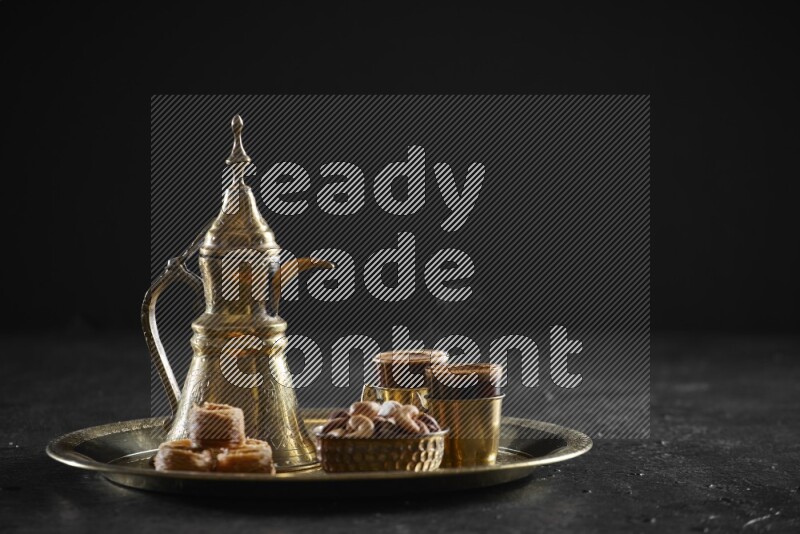Oriental sweets with nuts and a drink on a metal tray in a dark setup