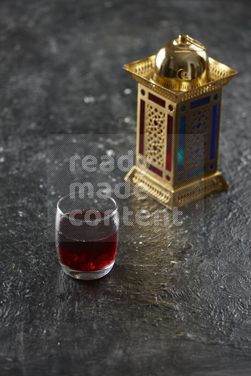 A golden lantern with different drinks, dates, nuts, prayer beads and quran on textured black background
