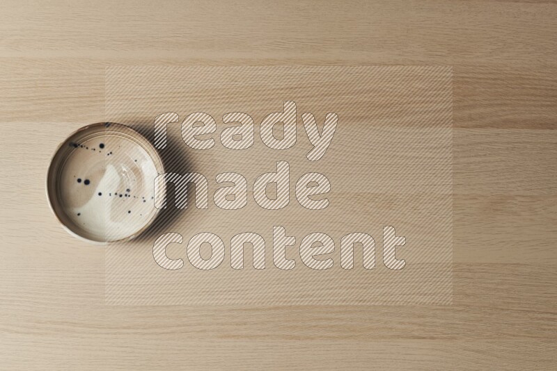 A multicolored pottery plate on light wooden background