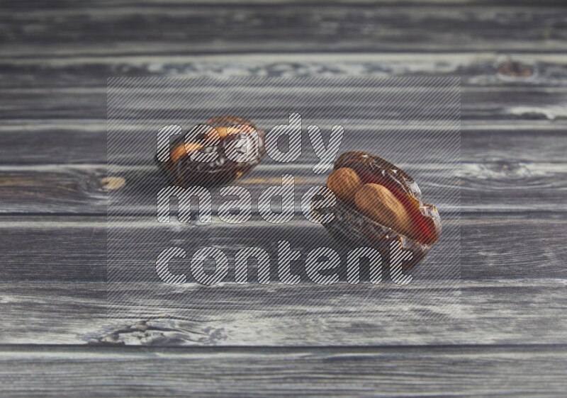 two almond stuffed madjoul dates on a wooden grey background