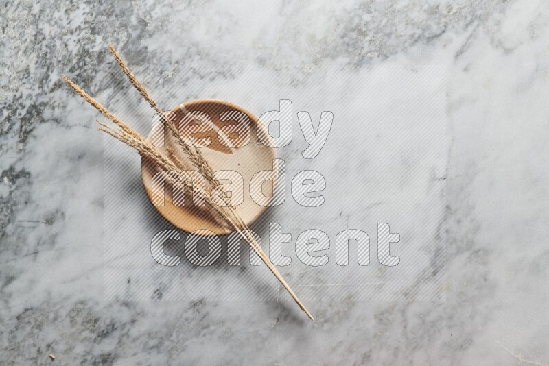 Wheat stalks on multicolored pottery plate on grey marble background
