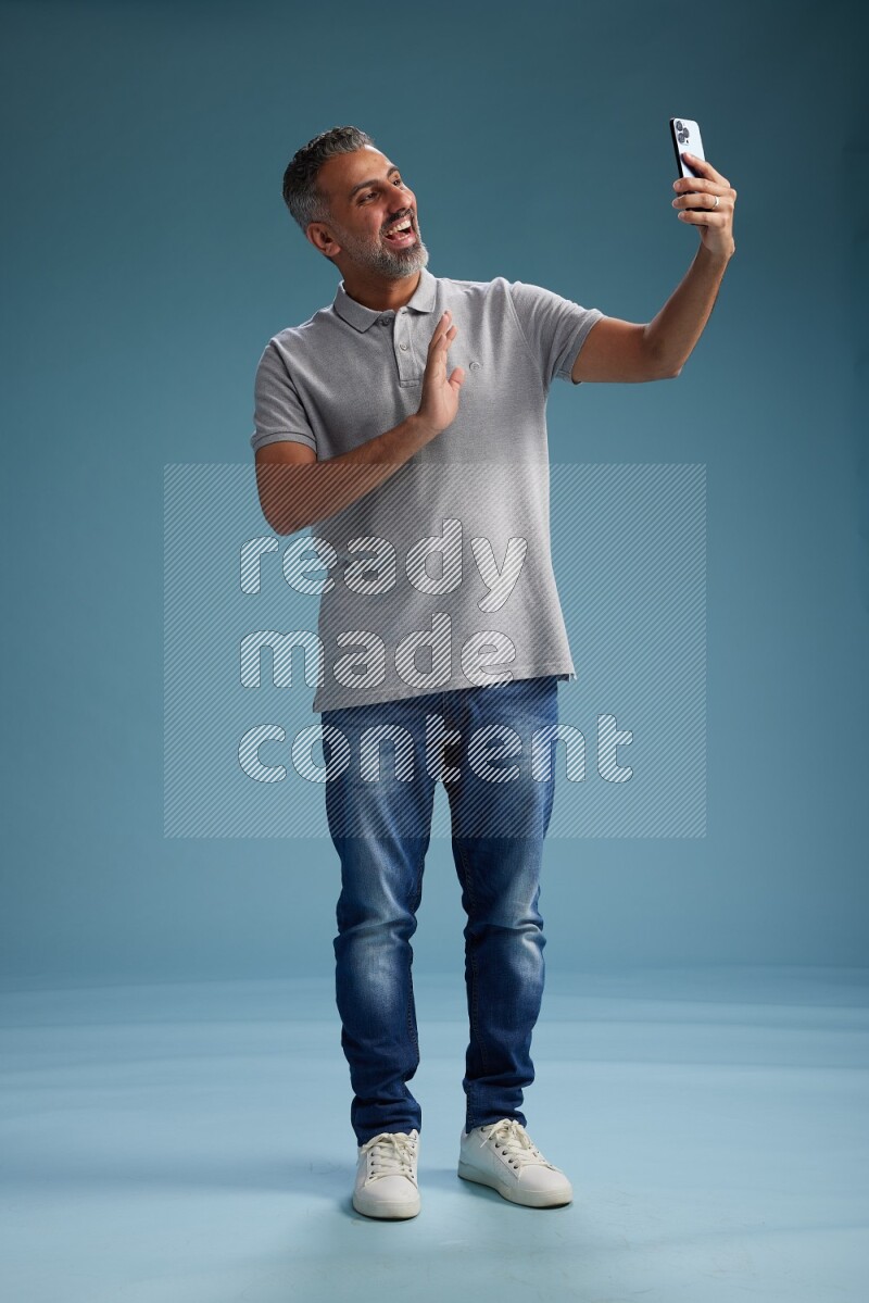 Man Standing taking selfie on blue background